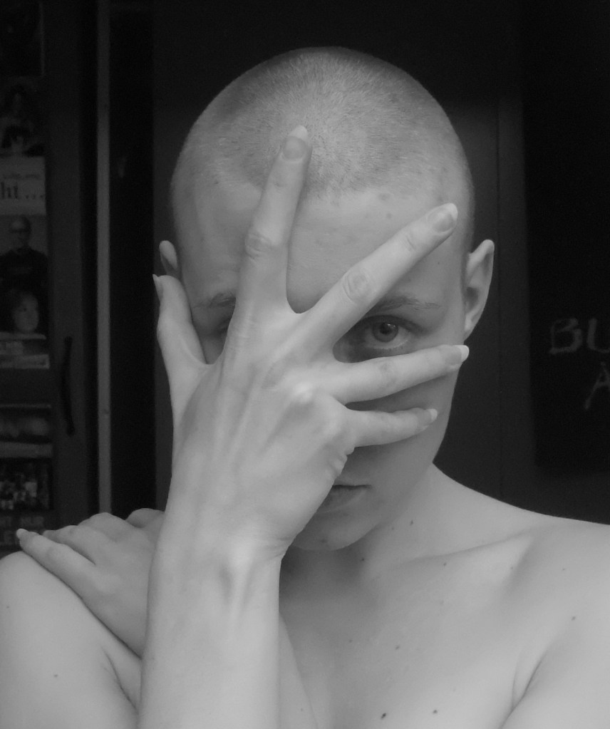 frau mit glatze, hand vor dem gesicht nur ein auge frei