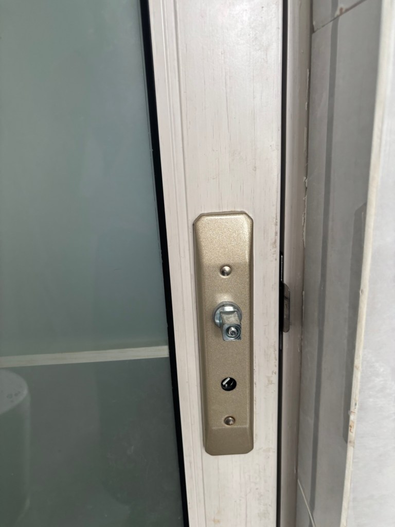 Eine verschlossene Tür. An der Stelle, an der die Klinke sein sollte, ist lediglich der Stumpf einer Vierkantschraube