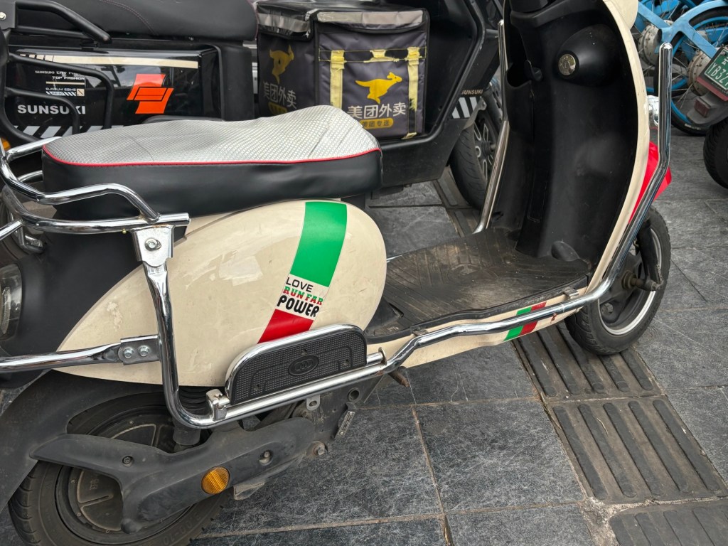 Auf einem Roller ist in rot, grün und schwarz der Aufkleber „Love Run Far Power“ angebracht.