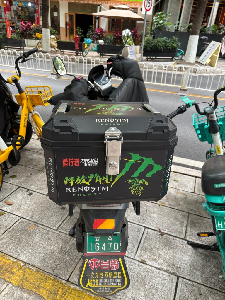 Das Topcase eines Rollers ist mit dem Schriftzug und der Farbgebung der Energydrinkmarke „Monster“ beklebt. Nur sind die Buchstaben in anderer Reihenfolge. Der Schriftzug ergibt: „Renøstm“