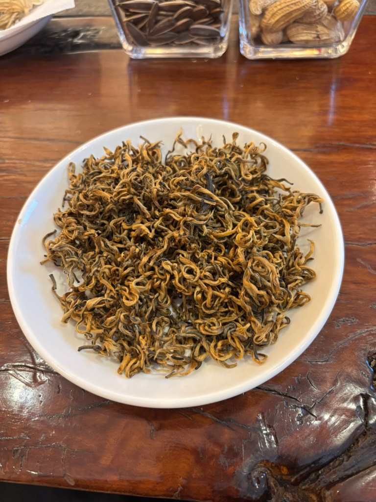 Hellbraune, getrocknete Teeblätter liegen als Haufen auf einem Porzellanteller