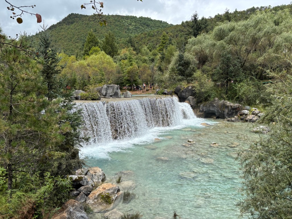 Ein breiter Wasserfall, der sich in einen hellblauen See ergießt